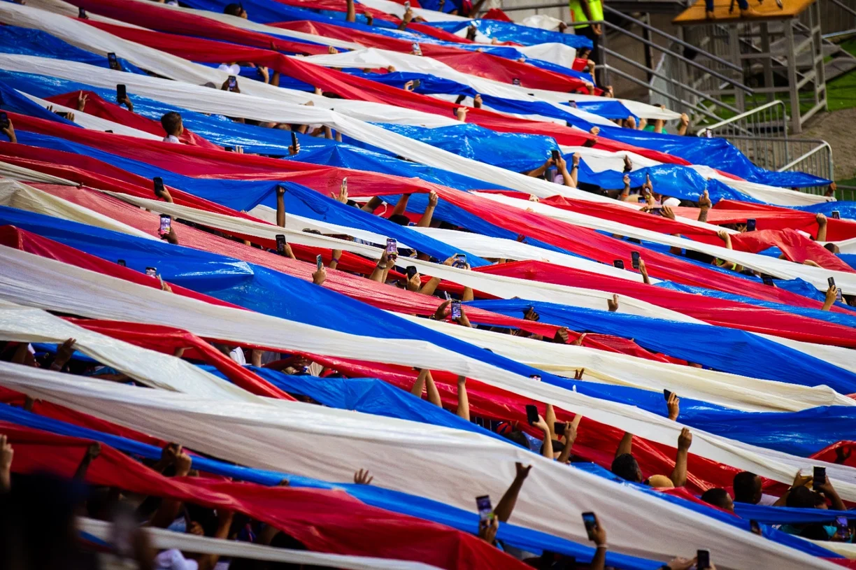 Torcida do Bahia nas arquibancadas com faixas azuis, vermelhas e brancas